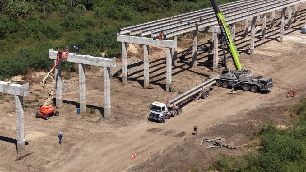 Guindaste ergue viga de concreto para posicionamento em pilares de obra rodoviária. Guindaste ergue viga de concreto para posicionamento em pilares de obra rodoviária.