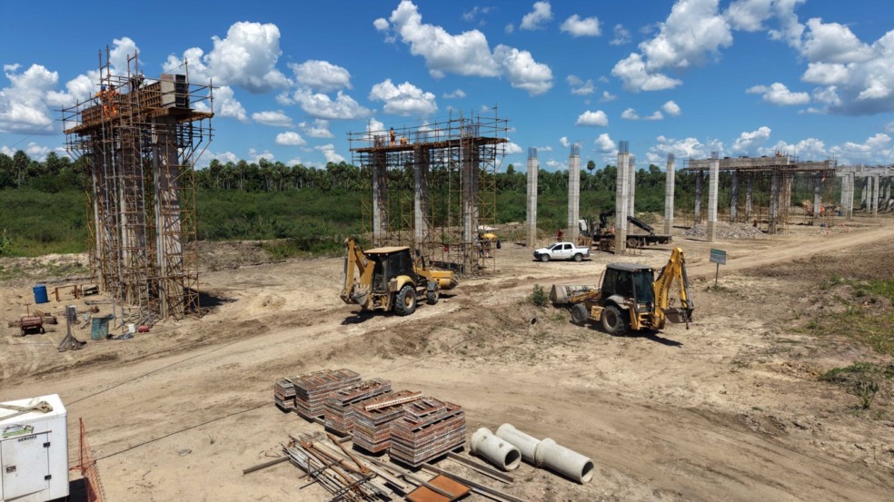 Retroescavadeiras e caminhões operam em grande obra rodoviária cercada por vegetação. Retroescavadeiras e caminhões operam em grande obra rodoviária cercada por vegetação.