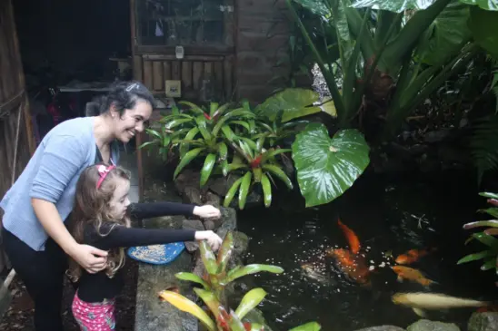 Alícia e a mãe Francini alimentando os peixinhos coloridos, que ficam na casa da família (Foto: Juliana Bencke/Folha do Mate)