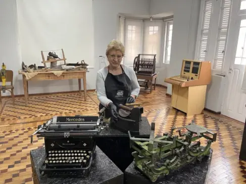 Organizadora das exposições, Beatriz Colombelli, junto ao salão principal, onde é montada a exposição ‘Trabalho: ferramentas diversas utilizadas no dia a dia’. Nesse andar, houve obras de restauro nas paredes, aberturas, piso e forro (Foto: Débora Kist/Folha do Mate)