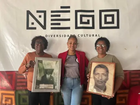 Maria Isabel com a foto do pai, João Generoso dos Santos, o fundador e primeiro presidente do Négo; Jaqueline e Maria Elisete com a foto de Leobaldo Rodrigues, conhecido por Tio Béco, um dos presidentes mais populares do Négo, o criador da expressão ‘Rua Grande’ para a Osvaldo Aranha, principal rua de Venâncio, onde são realizados os desfiles de Carnaval. (Foto: Luana Schweikart)