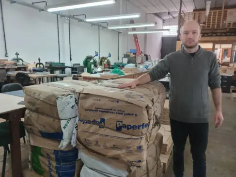 Auxiliar Jonas Ruppenthal com sobras e aparas de papel da produção que obterão destinação correta (Foto: Alan Faleiro)