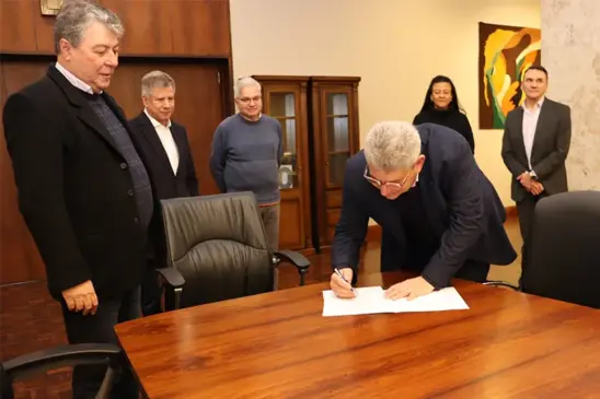 Kalil Sehbe Neto assinando o termo de posse, no Salão Nobre da sede do Banrisul, na presença do presidente Fernando Lemos e diretoria. (Foto: Banrisul/ Divulgação)