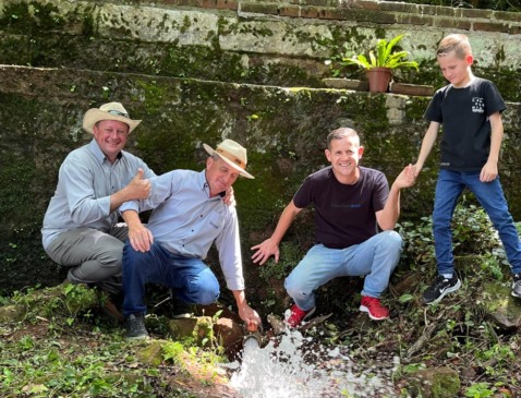 Profissionais da CTA (à esquerda), Junior e seu filho mostram a boa vazão que tem o reservatório (Foto: Juan Grings)